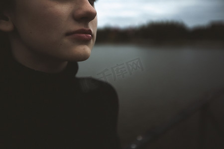 年轻孤独的少女望向远方，独自放弃自己，在水边的码头上思考，感到无聊沮丧晚上坐在码头上