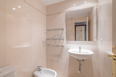 舒适的小浴室，墙上贴着米色瓷砖、梳妆台、卫生间和坐浴盆，墙上挂着镜子。