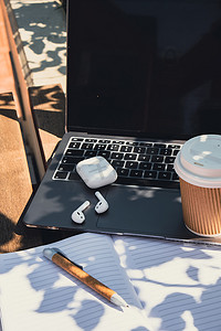 用带无线耳机的纸质笔记本电脑带走工艺回收纸杯中的咖啡。