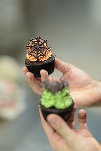 绿色怪兽摄影照片_糕点师面包师准备万圣节绿色橙色怪物纸杯蛋糕手工制作
