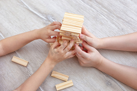 孩子们的手在地板上收集了一座木块塔。