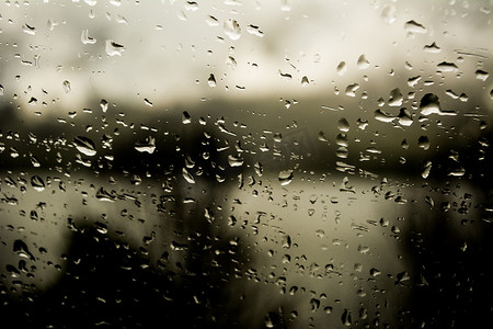 秋风秋雨摄影照片_雨滴落在深色背景、喜怒无常和黑暗、秋雨或冬雨的窗户上。