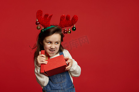 鹿角圈里淘气活泼的女婴，微笑着看着复制广告空间，打开圣诞 gif 盒