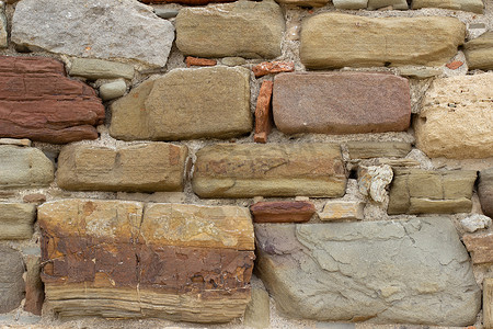 旧石墙由米色、赭石、红色和棕色的各种方形天然石材制成。