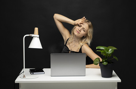 沮丧、不快乐的笔记本电脑用户女性在工作台上用电脑摸头，经历压力、疲劳、倦怠、收到坏消息。