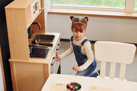 穿休闲服的小女孩在厨房玩玩具玩得很开心