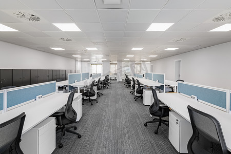 宽敞空旷的灰色办公室，配有舒适的办公家具，没有设备，为不同方向的员工提供区域。