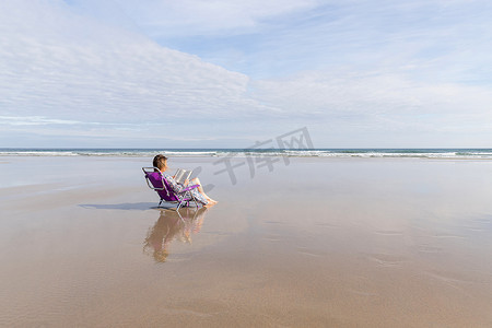 坐在沙滩椅上看书的女人