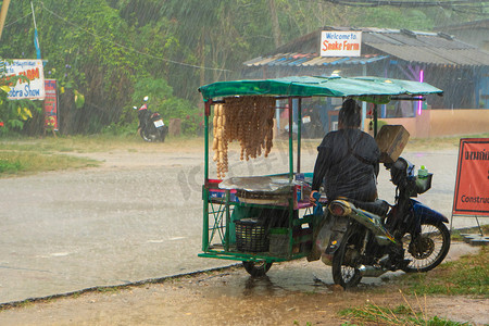 雨中街道摄影照片_雨中骑自行车卖小吃的小贩