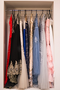 为活动租用礼服。特写绣有宝石和亮片的粉红色婚纱，挂在衣架上，与其他礼服一起悬挂。