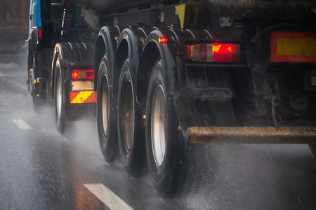 有选择地聚焦在日光城市中快速移动的重型卡车车轮的雨水飞溅流。