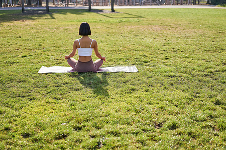 年轻女性在晨间公园冥想、放松、呼吸练习和健康训练课程的后视