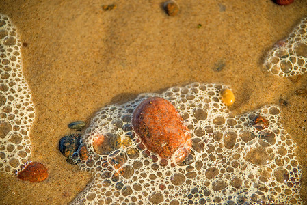 与海浪和小卵石泡沫的沙滩