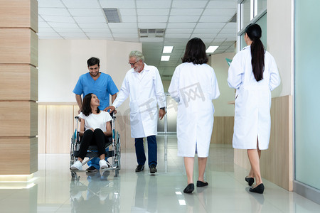 医生和护士在无菌走廊用轮椅运送女病人。