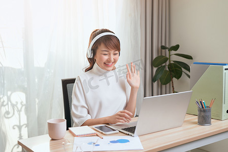 美丽的亚洲女人在家里工作的地方用笔记本电脑打电话视频。