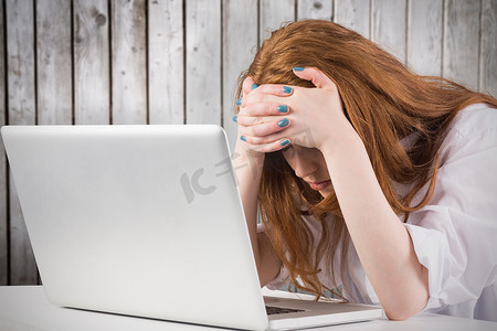 在笔记本电脑上工作的漂亮红发女郎的合成图像