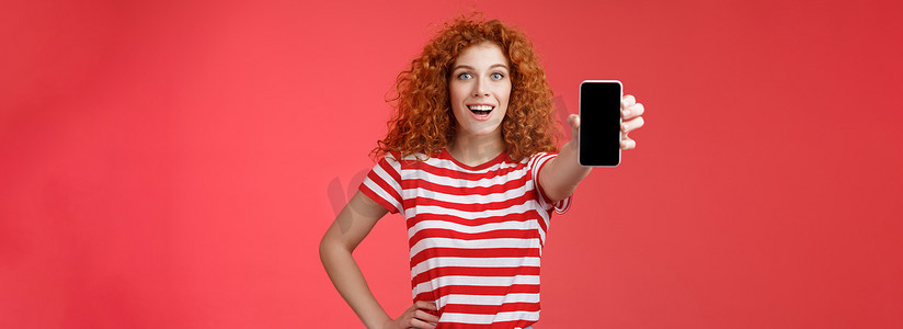 欢快迷人的魅力欧洲红发女孩卷发秀智能手机屏幕快乐地微笑推广应用程序建议推荐良好的应用程序社交媒体页面红色背景