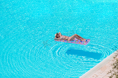 暑假游泳摄影照片_在豪华游泳池享受暑假的年轻美女