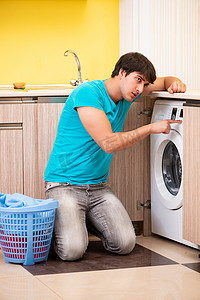 洗衣洗衣服摄影照片_在家洗衣服的年轻丈夫