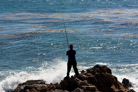 海浪汹涌摄影照片_男人在汹涌的海浪中捕鱼