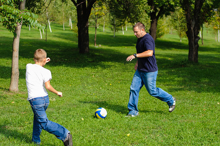 和父亲一起踢足球的小男孩