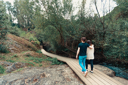 在森林里的河边散步的年轻夫妇