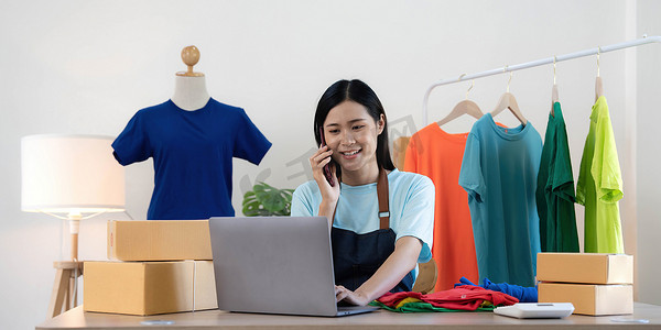 确认订单摄影照片_美丽的亚洲女性在线卖家通过电话确认客户的订单，创办小型企业的中小企业主女企业家在家里使用笔记本电脑、包装和交付情况概念。