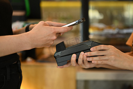女性顾客拿着手机扫描二维码的镜头，在咖啡店进行非接触式移动支付