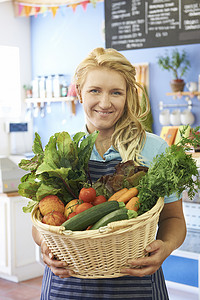 农产品商店摄影照片_在商店里提着一篮子新鲜农产品工作的妇女