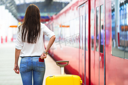 年轻的白人女孩带着行李在车站乘火车旅行