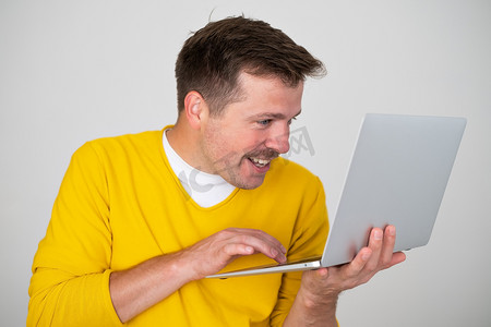 拿着膝上型个人计算机的微笑的有魅力的人，在互联网上冲浪
