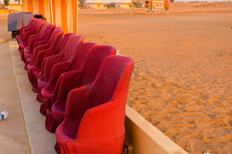 限时特供摄影照片_在背景为沙漠的表演中，红色泥土藤椅沙发的特写镜头，沙发上有小黄砖墙，供游客就座