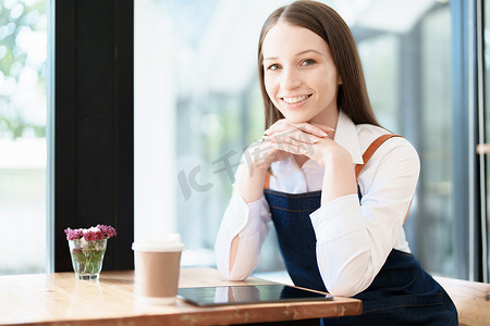 围裙摄影照片_开始并开设一家小企业，一位年轻的亚洲女性围着围裙站在咖啡店吧台前露出笑脸。