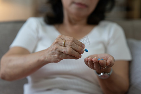 亚洲老年妇女在家吃药。