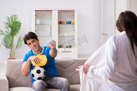 年轻的妻子正试图引诱丈夫不看足球