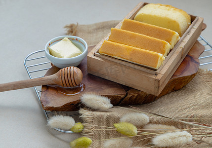 蛋糕蜂蜜摄影照片_木盒中的四片黄油蛋糕，配以黄油和蜂蜜。