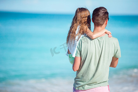 沙滩上的孩子摄影照片_在热带海滩的家庭一起走在热带卡莱尔湾海滩上，在加勒比安提瓜岛有白色的沙滩和绿松石海水。