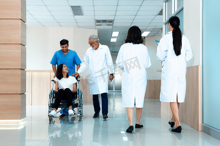 医生和护士在无菌走廊用轮椅运送女病人。