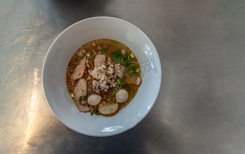 泰式辣汤面配猪肉和鱼丸在白色陶瓷碗中。