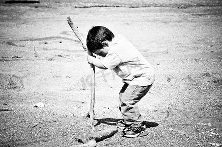 男孩玩沙子里的棍子
