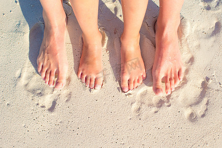 在白色沙滩上特写母亲和孩子的脚