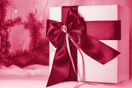 一份圣诞礼物，在浅色背景上用冷杉树枝装饰着美丽的蝴蝶结。