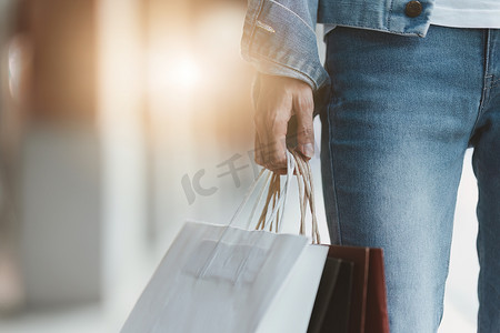 亚洲时尚女性提着购物袋在购物中心散步，同时进行限时促销