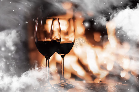 大气冬季背景摄影照片_冬季气氛和圣诞假期，壁炉前的酒杯在窗玻璃上覆盖着雪花效果，假期背景