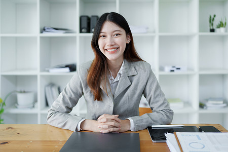 一位女企业主的画像，她在工作中使用电脑和财务预算文件成功地投资了她的企业时，脸上挂着快乐的笑脸