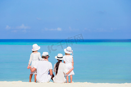 沙滩上一个穿着白色衣服的幸福家庭的背影