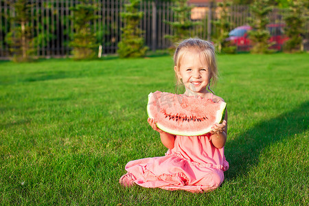 绿草上手里拿着大块西瓜的小女孩