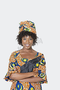 灰色背景中身穿非洲印花服装站立双臂交叉的年轻女性肖像
