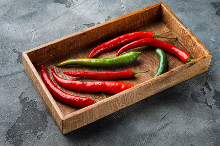 成熟的红绿辣椒，在木箱里，灰色背景