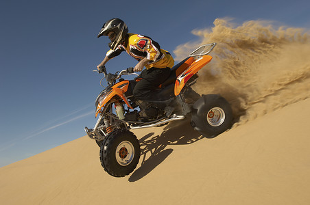 蓝天沙漠中一名男子骑四轮摩托的低视角